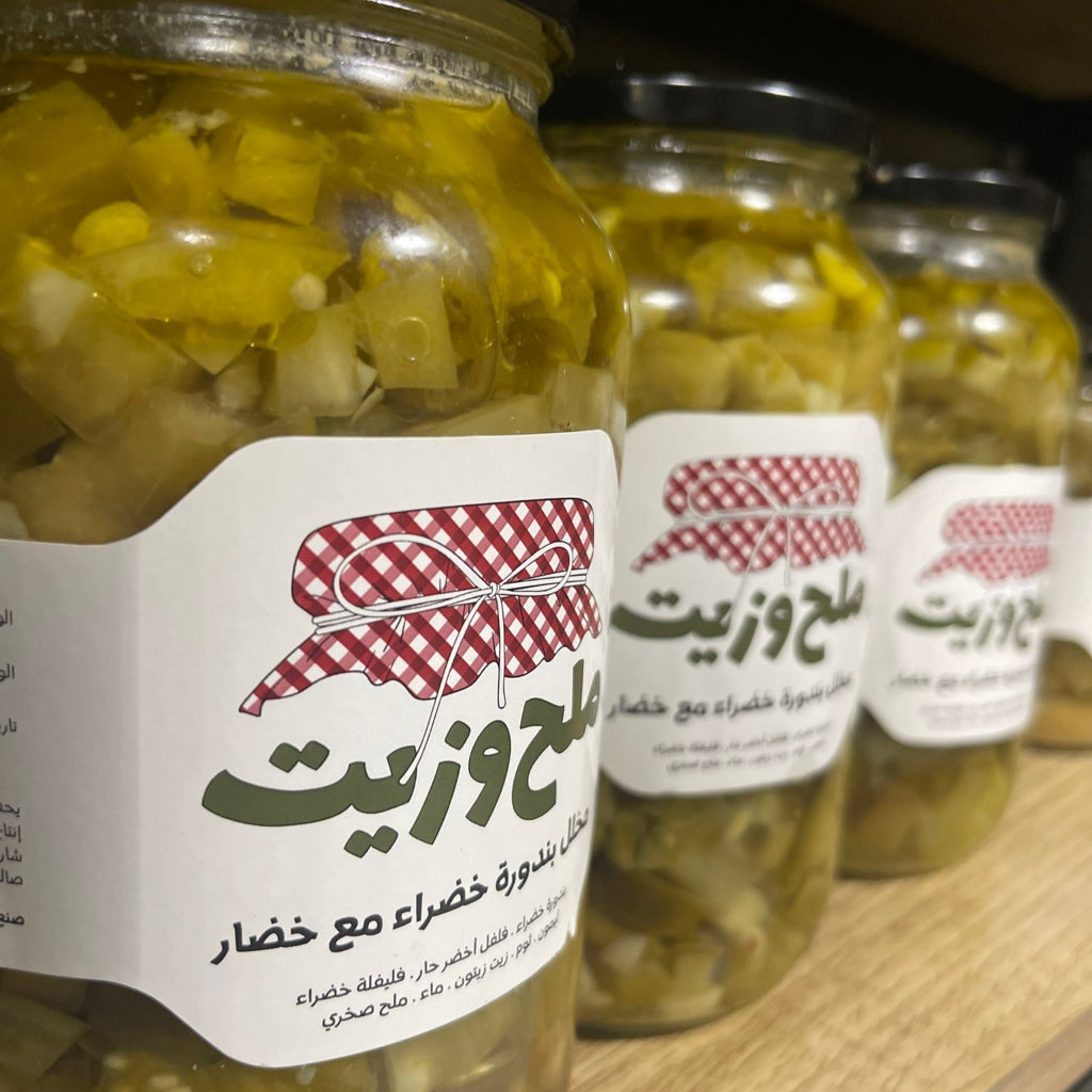 مجموعة من المرطبانات الزجاجية تحتوي على مخلل بندورة خضراء مع خضار